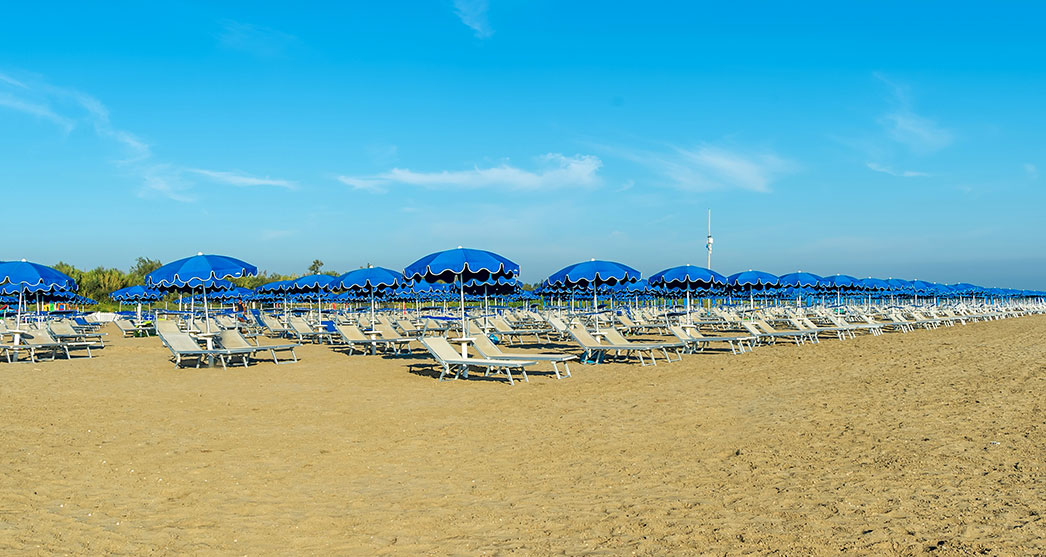 lettini crema e ombrelloni blu da spiaggia ad Albarella