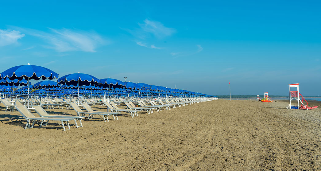 veduta laterale dei lettini da spiaggia degli ombrelloni e della torretta di salvataggio