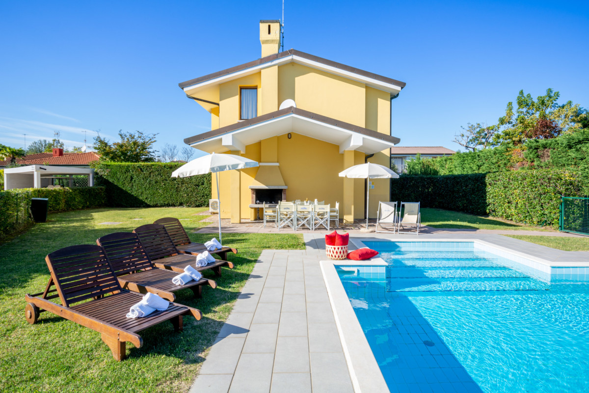 Giardino di villetta con piscina e sedie sdraio